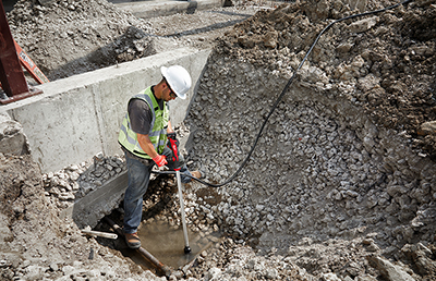 A Milwaukee M12 Stick Transfer Pump pumps standing water out of a jobsite.