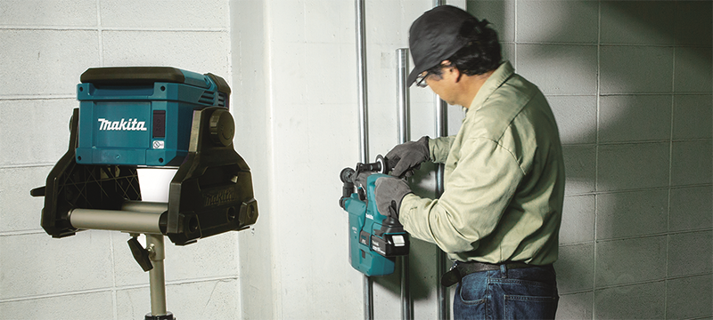 A worker uses a DML811 Work Light on a stand to brighten his workspace.